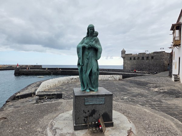 Estatua de bronce de la Virgen del Carmen sosteniendo al Niño frente al mar.