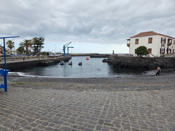Vista panorámica de la Playa del Muelle con barcas amarradas y la Casa de la Real Aduana al fondo en Puerto de la Cruz, Tenerife.