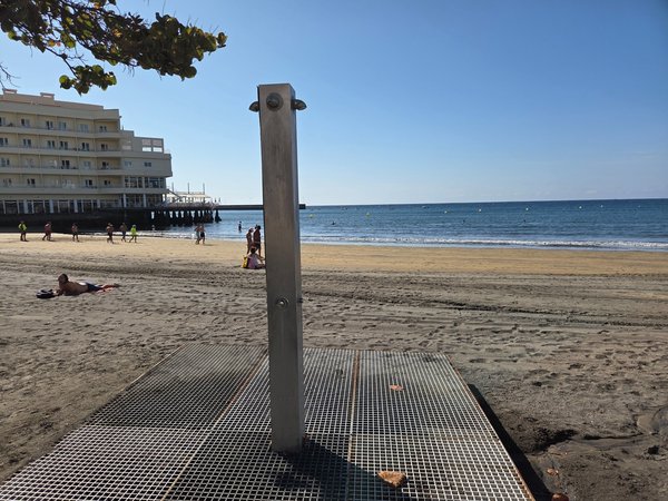 Ducha exterior en la arena de Playa El Médano con el mar de fondo.