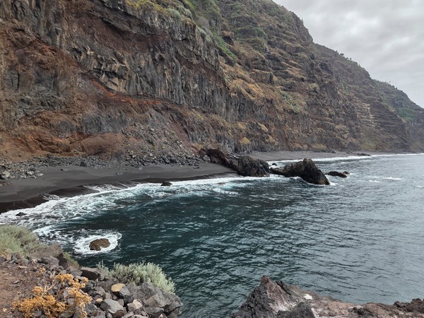 Panorámica de la Playa de la Garañona con la franja de arena negra y los acantilados verticales de El Sauzal.