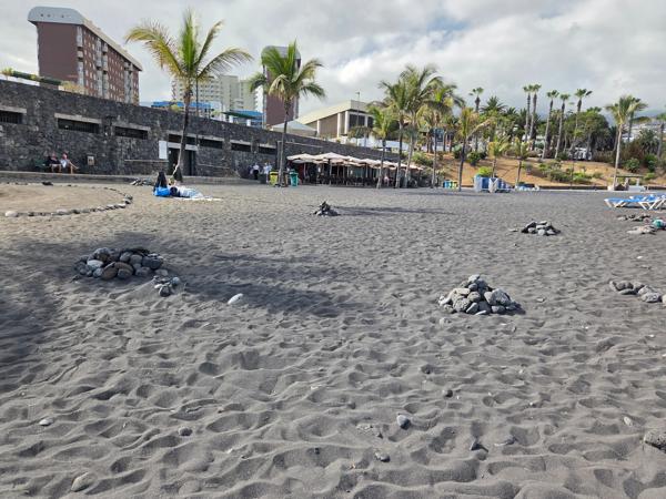 Pequeños montículos de piedras basálticas sobre la arena volcánica de Playa Jardín.