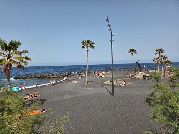 Zona de arena volcánica y solárium de la Playa de Punta Larga con espigones protectores.