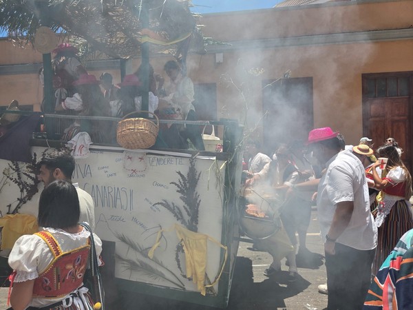 Carro-tenderete humeante donde asan carne mientras reparten comida y bebida.