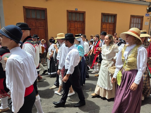 Desfile de romeros con trajes tradicionales: chalecos, faldas de rayas y sombreros.
