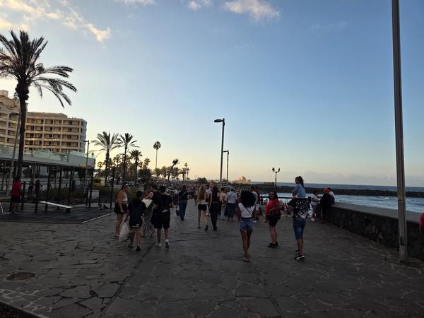 Cientos de personas se dirigen a la playa por el paseo marítimo para celebrar la Noche de San Juan en Puerto de la Cruz.