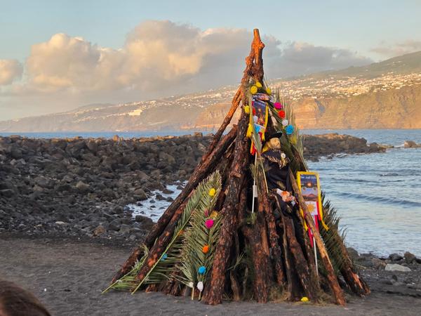 Detalle de la hoguera decorada con flores, palmas y un muñeco tradicional antes del encendido.