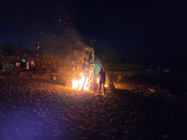 Momento en que se prende fuego a la hoguera principal mientras se alzan chispas en la oscura noche de San Juan.
