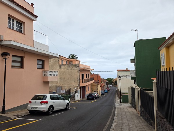 Barrio con vistas al mar Vista de una calle residencial en Tacoronte con viviendas de varias alturas y el océano al fondo.