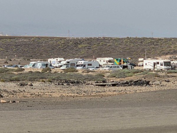 Autocaravanas y coches estacionados junto a la playa de La Tejita con vistas al mar