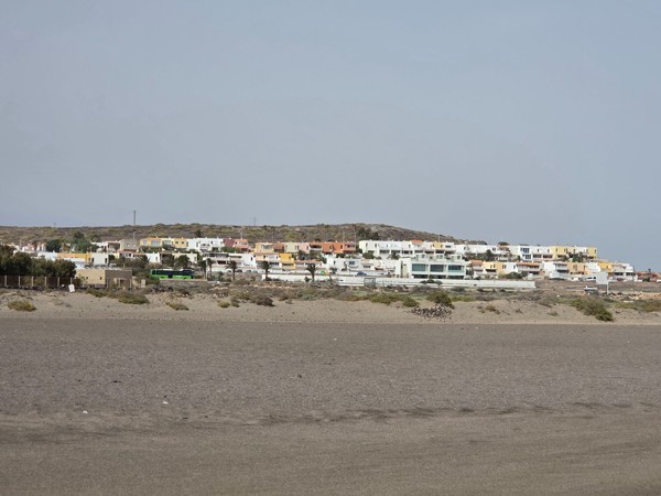 Zona residencial de La Tejita con casas blancas y coloridas frente al océano