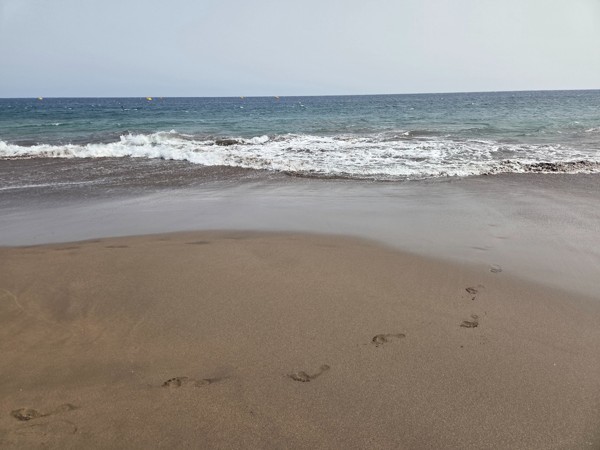Primer plano de la arena húmeda y las olas suaves en la orilla de La Tejita