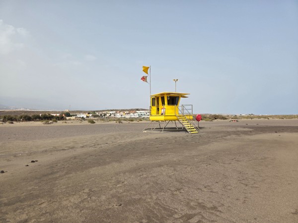 Puesto amarillo de socorristas situado sobre la arena oscura de La Tejita
